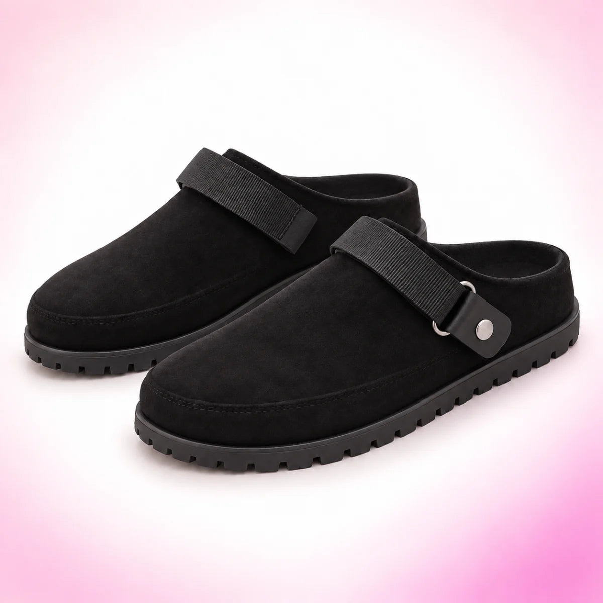 Black strappy clogs on a blush pink studio background