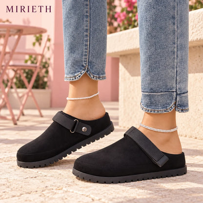 Black strappy clogs styled with blue jeans at a blush cafe terrace