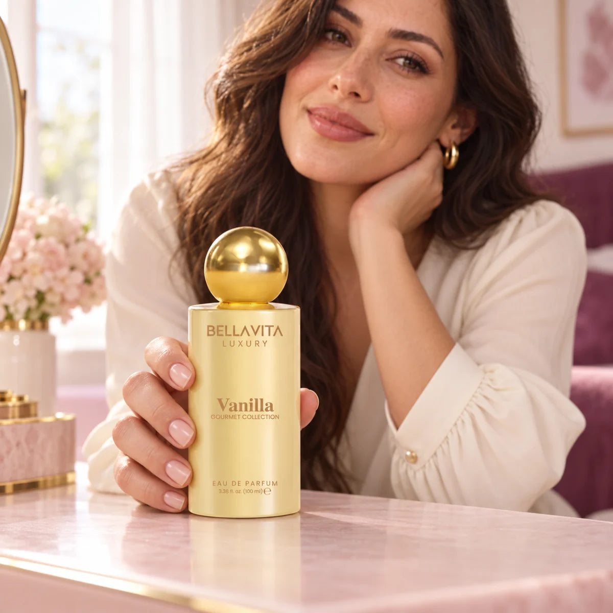 Woman holding a closed BellaVita Vanilla perfume bottle at a vanity
